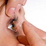 girl inserts lens into eye